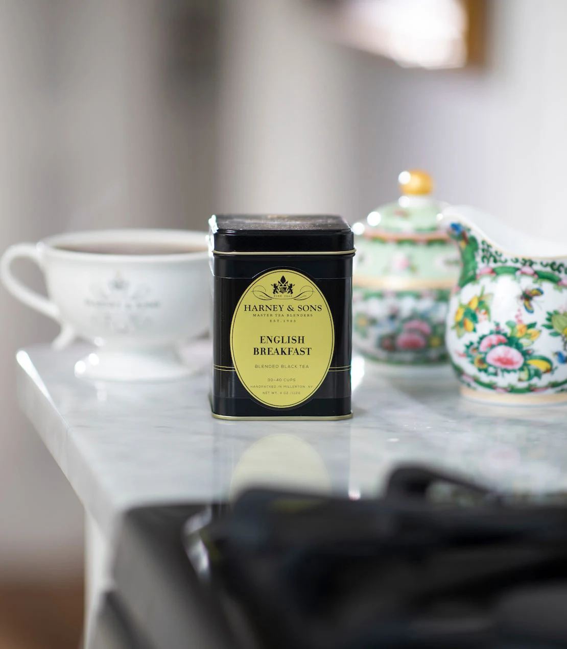 Harney & Sons English Breakfast tea tin on a table with a teacup and floral teaware