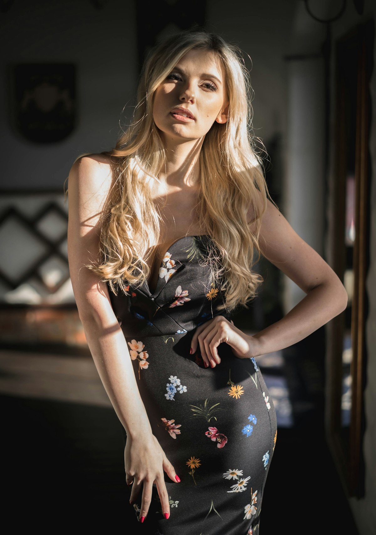 Woman wearing a dark floral dress beside a window