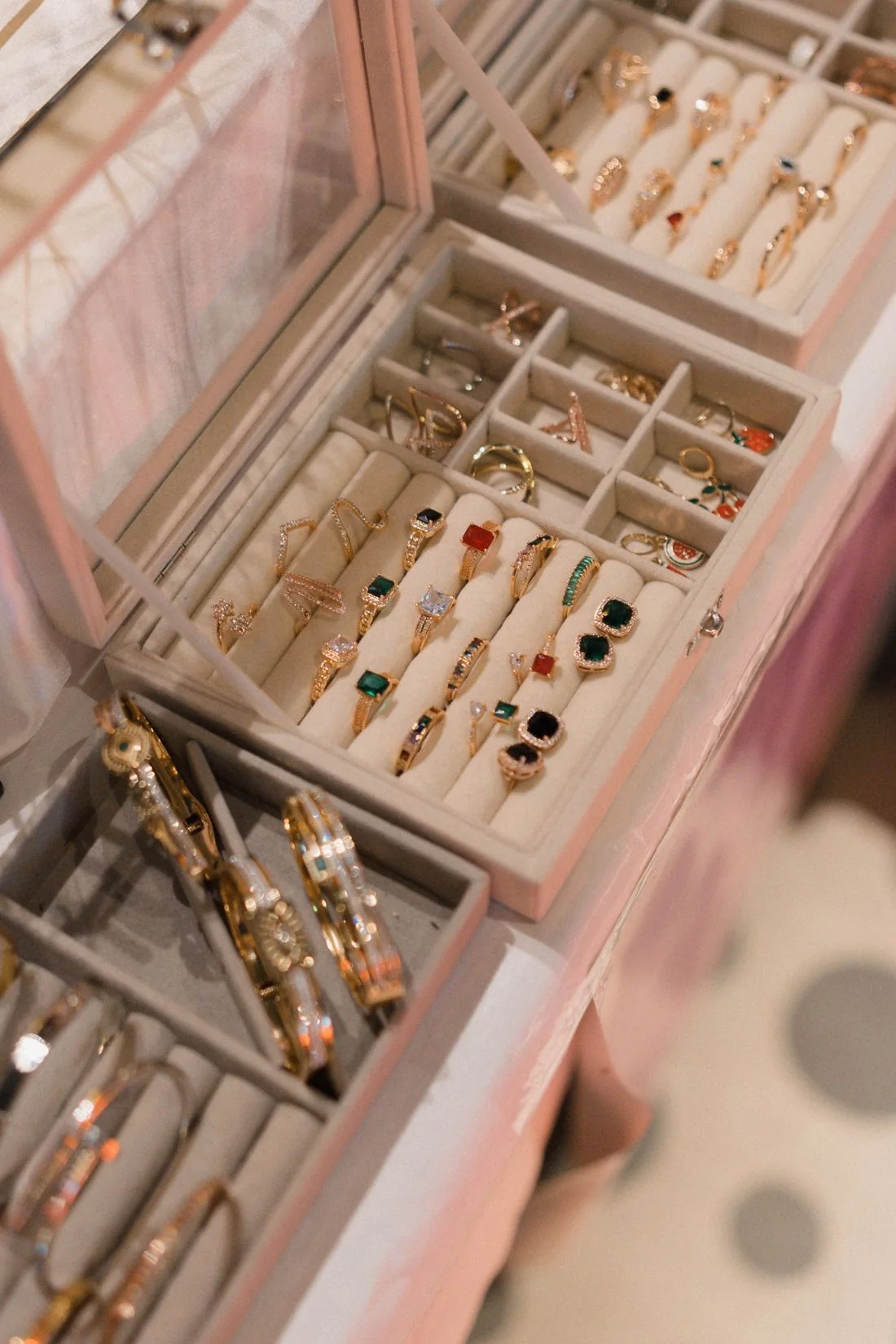An open pale jewellery box holding rings, bracelets and other pieces