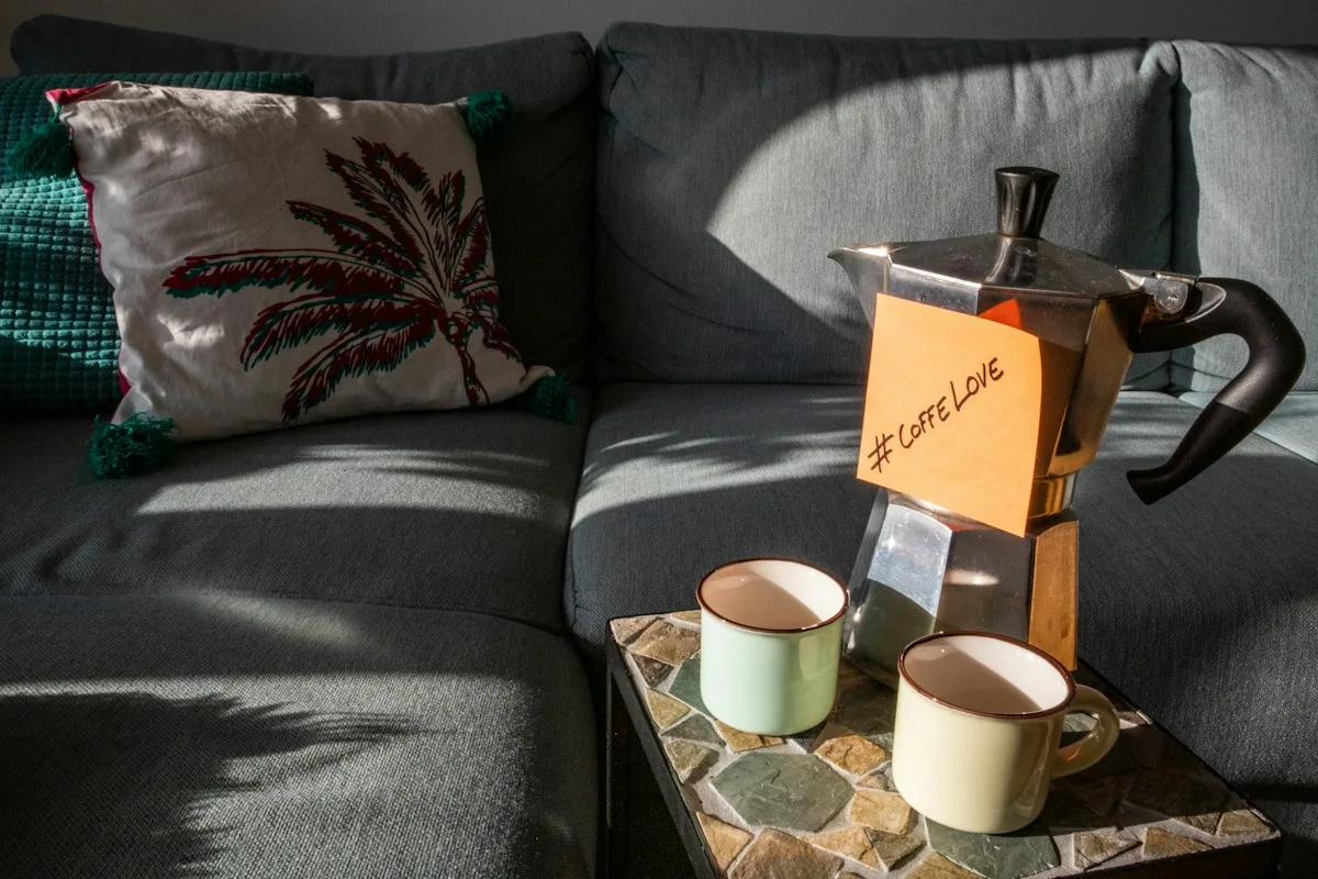 Two cups and coffee supplies beside a sofa