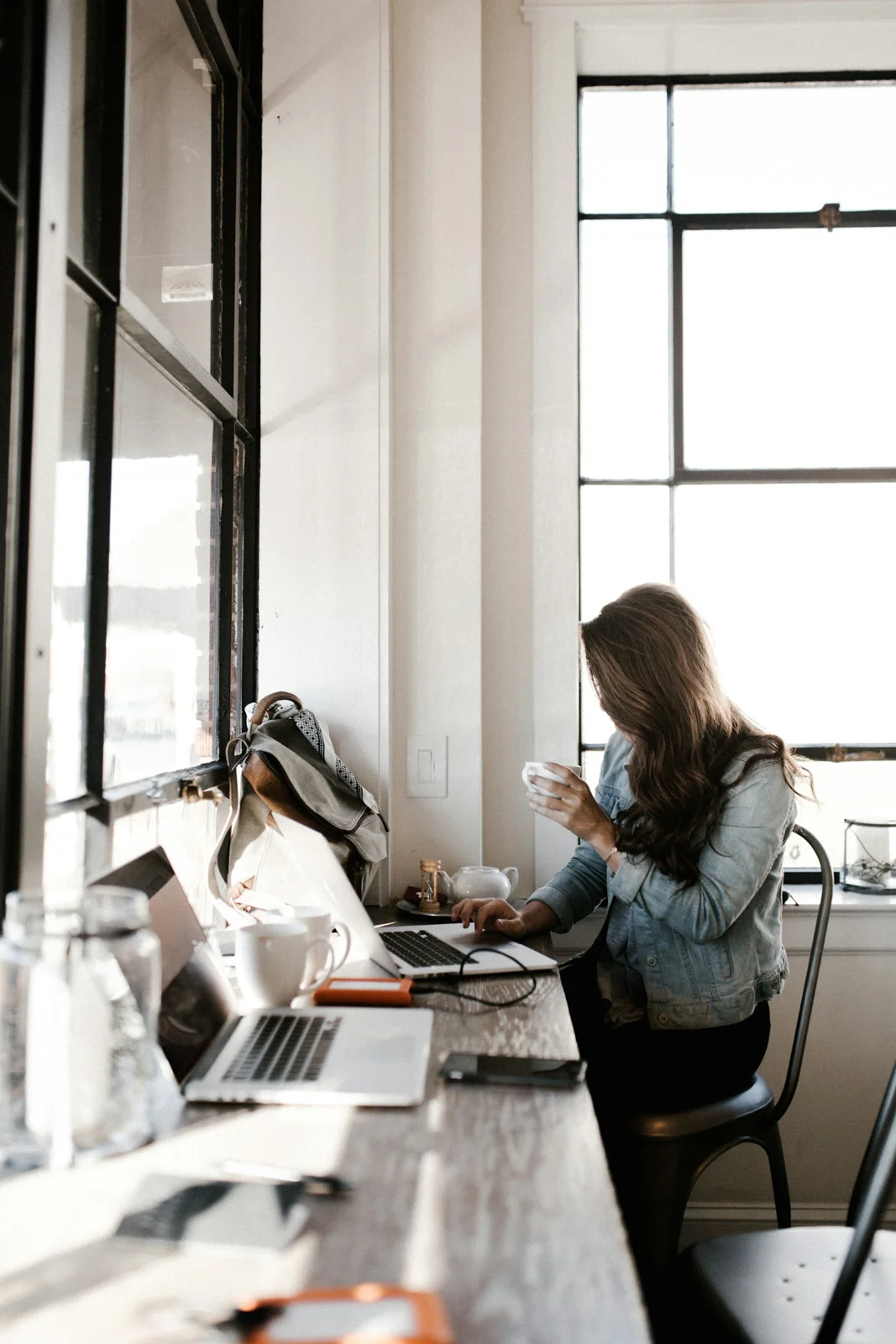 Woman in a denim jacket working at a cafe table